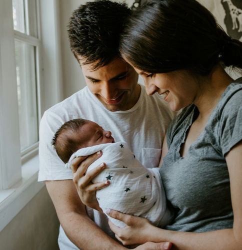 woman holding baby beside man smiling